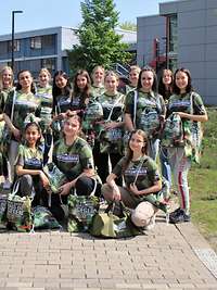 Eine Gruppe junger Frauen gekleidet in Polygonfarbenen T-shirts stehen vor einem Gebäude.