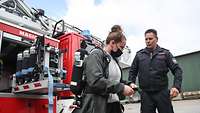 Ein Feuerwehrmann erklärt einem Mädchen wie Feuerlöschmittel funktionieren.