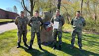 Mehrere Soldaten vor einem Wappen. Einer hält eine Urkunde in der Hand
