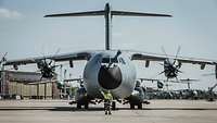 Ein Fluglotse steht vor dem Transportflugzeug der Bundeswehr und zeigt dem Piloten den erhobenen Daumen.