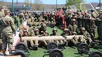 Mehrere Soldaten hieven einen schweren Baumstamm.
