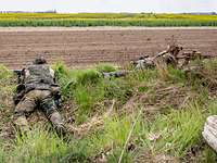 Sicherung des Flugfeldes Zwei Soldaten liegen mit Waffe im Anschlag im Gras am Feldrand.