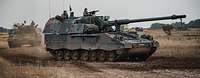 Zwei Panzerhaubitzen 2000 fahren im Gelände.