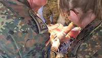 Ein Soldat und und Soldatin behandeln eine männliche Person