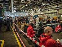 Im Rumpf der "Rotterdam" Viele Menschen sitzen nebeneinander im Rumpf des Docklandungsschiffs Rotterdam