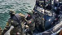 Mehrere Soldaten steigen in ein Boot ein
