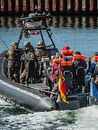 Soldaten fahren mit Zivilisten in einem Speedboot.