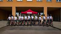 13 Fahrradfahrer stehen nebeneinander in der Kaserne kurz vor dem Start der Radtour.