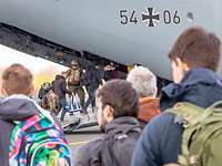 Einsteigen in den A400M Personen stehen in einer Schlange vor einem Flugzeug. Ein Soldat hilft beim Einsteigen.