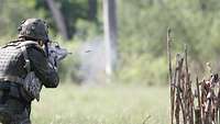 Ein Soldat auf einer Wiese feuert ein Gewehr G36 ab.