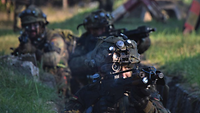 Mehrere bewaffnete Soldaten kämpfen in einem Grabensystem.