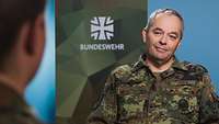 Generalleutnant Alfons Mais sitzt einer Soldatin gegenüber und spricht mit ihr.