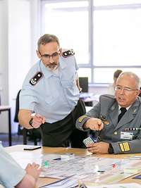 Kodalle blickt auf das Spielfeld einer Spielgruppe. Die Teilnehmenden fragen ihn etwas