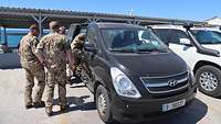 Vier Soldaten steigen in einen schwarzen Minivan ein