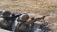 Zwei Soldaten stehen mit ihrem Gewehr im Anschlag in einem Schützenloch und schießen. 