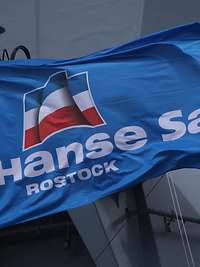 Eine blaue Flagge mit der Aufschrift „Hanse Sail Rostock“ weht im Wind.