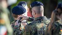 Ein Soldat bekommt nach seiner Beförderung die Schulterklappen aufgesteckt.