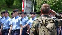 Ein Soldat salutiert den vorbei marschierenden Soldaten