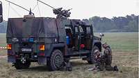 Zwei Soldaten an ihrem Fahrzeug beim Kartenstudium.