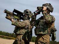 Jede Nation bringt besondere Fähigkeiten mit Ein Soldat steht mit einer Flugabwehrrakete auf der Schulter, der zweite schaut durch ein Fernglas.