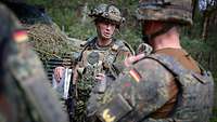 Multinational schon auf höchster Ebene Drei ranghohe Soldaten stehen hinter einem Panzer und sprechen miteinander.