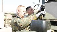 Zwei Soldaten machen einen Ölwechsel an einem Stromerzeuger