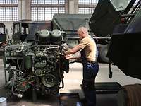 Ein Soldat schraubt an einem Motorblock in einer Halle
