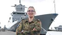 EIne Marinesoldatin steht an einer Pier und blickt in die Kamera.