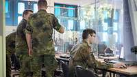 Soldaten sprechen vor mehreren Computern miteinander