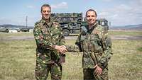 Zwei Soldaten geben sich die Hand vor einem Einsatzfahrzeug