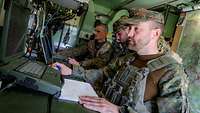 Wichtige Verbindung Drei Soldaten sitzen im Innenraum einer kleinen Kabine an Computern.