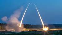 Zwei Raketenwerfer schießen mit gleißender Lichtspur ihre Raketen ab.