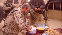 Soldat steht am Auto und bereitet Essen vor