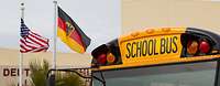 Ein gelber Schulbus und die amerikanische sowie die deutsch Flagge.