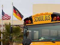 Der School Bus fährt auch zu den Auslandsschulen der Bundeswehr. Ein gelber Schulbus und die amerikanische sowie die deutsch Flagge.