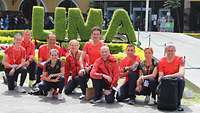 Sportlerinnen und Sportler vor einem Schild Lima