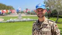 Portrait von Oliver B., der vor den zirka 30 Flaggenmasten vor dem UNIFIL-Hauptquartier steht