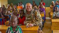 Ein Soldat sitzt gemeinsam mit Schulkindern im Klassenzimmer