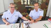 Zwei Männer in Uniform sitzen an einem Tisch.