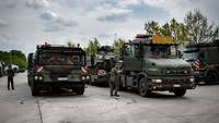 Ein deutscher und ein belgischer Schwerlasttransporter stehen nebeneinander.