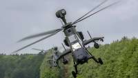 Zwei Hubschrauber fliegen sehr schnell und sehr nah am Boden.