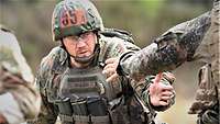 Ein Soldat reicht bei einem Wettkampf einem anderen Soldaten die Hand.