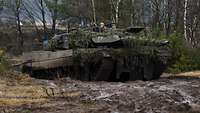 Ein Panzer fährt im Gelände. Zwei Soldaten schauen aus der Dachluke.