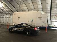 US Police beachht SARah Satelliten Ein amerikanisches Polizeiauto steht vor einem weißen Container