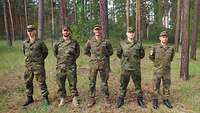 Fünf Soldaten stehen in Feldanzug auf der Wiese