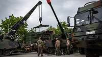 Motorwechsel Ein Kranausleger eines Panzers hebt ein Triebwerk aus einer Haubitze.