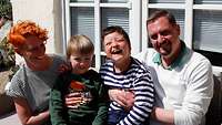 Eine Frau und ein Mann sitzen mit ihren zwei Kindern auf einer .