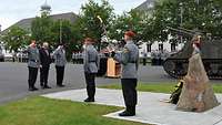 Kranzniederlegung Soldaten stehen vor und neben einem großen Stein. Zwei Tagen eine Fackel und zwei grüßen.