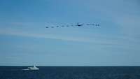 PHOTEX Flyby Mehrere Flugzeuge fliegen in der Luft über ein Boot, welches sich im Wasser befindet.