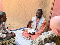 Ein Soldat im Gespräch mit einem Einheimischen in Mali Ein Soldat spricht mit zwei Männern sitzend auf einer Decke.